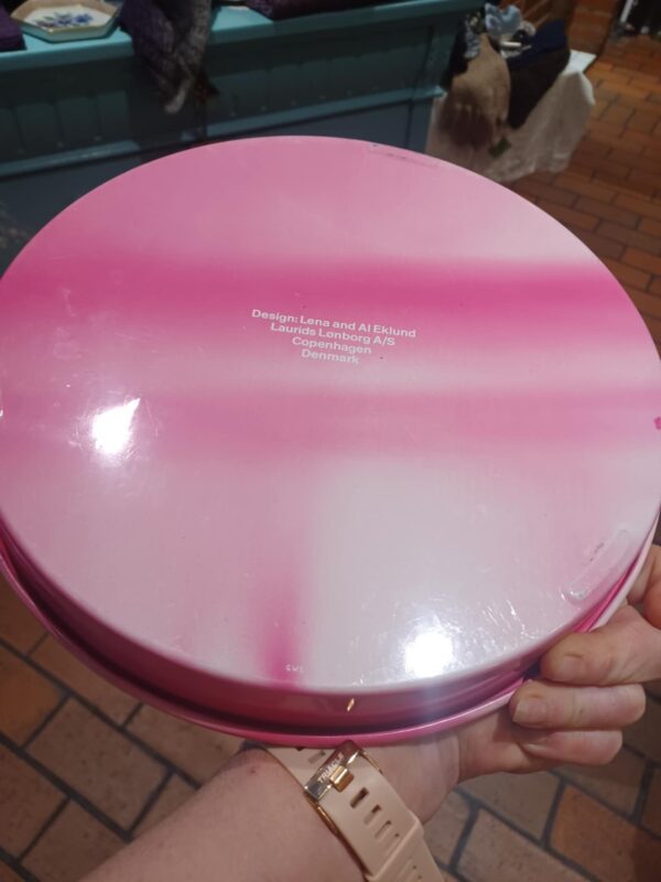 Bagsiden af et rundt pink gradient serveringsfad med teksten 'Design: Lena and Al Eklund, Copenhagen Denmark' påtrykt.