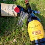 En porcelænsfigur af en beslagsmed og to flasker Gammel Dansk og Dr. Nielsens Bitter, ligger på græsset til en picnic.