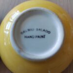 Bunden af en gul håndmalet tapasskål fra 'Del Rio Salado', hvor teksten 'HAND PAINT' er synlig.