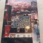 Bagsiden af 'Den sidste dans' af Ed McBain, med et billede af bygninger og bogbeskrivelse.