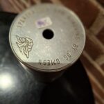 Toppen af en vintage metalsparebøsse med gravering 'Sparretårnet' og 'Omega'.