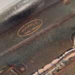 Nærbillede af mærkets logo 'Vulkolit - Dansk Arbejde' på en patineret mørkegrøn vintage rejsekuffert.