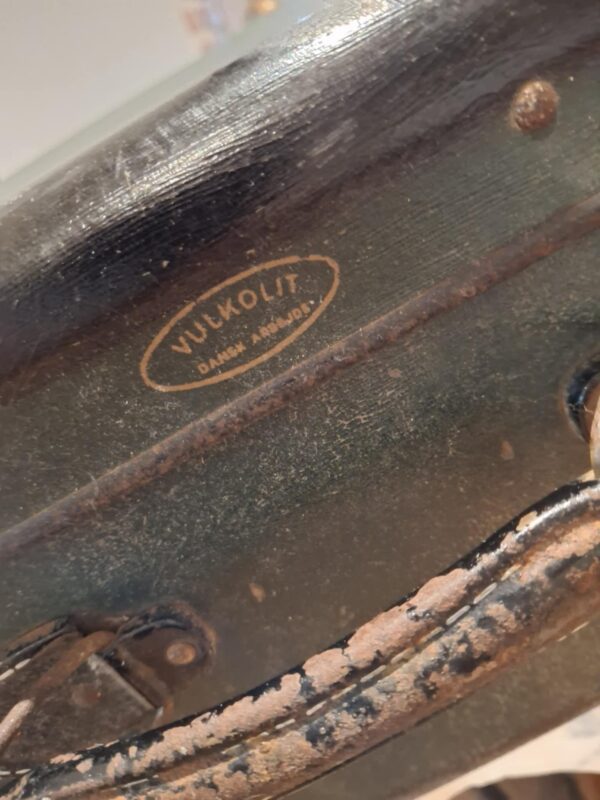 Nærbillede af mærkets logo 'Vulkolit - Dansk Arbejde' på en patineret mørkegrøn vintage rejsekuffert.