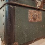 Nærbillede af det rustne lås på en mørkegrøn vintage Vulkolit rejsekuffert, der viser alder og patina.