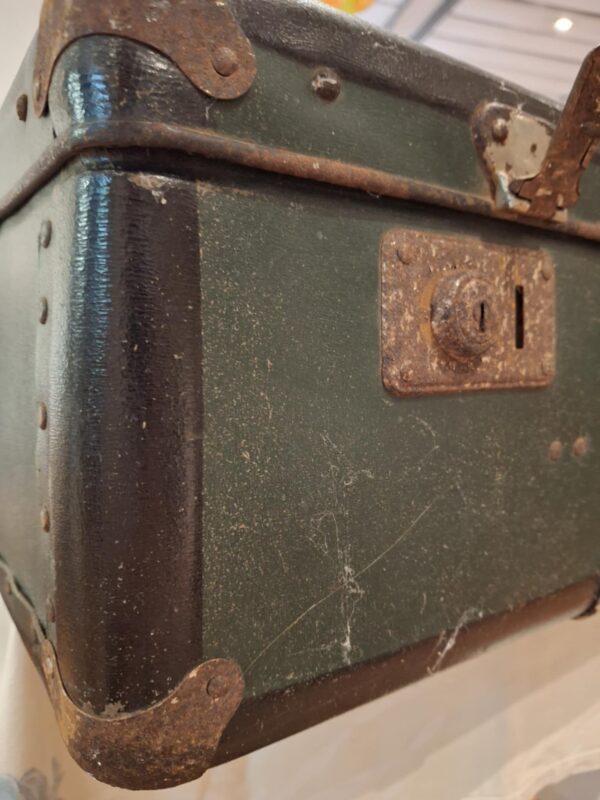 Nærbillede af det rustne lås på en mørkegrøn vintage Vulkolit rejsekuffert, der viser alder og patina.