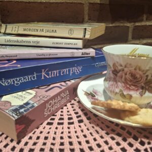 En stor stak 'Hvem Hvad Hvor' årbøger i forskellige årgange fra sort, hvid og orange rygdesign på et træbord.