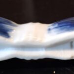 Nærbillede af en enkelt blå-hvid porcelænsholder med håndmalede blå striber og en hvid underside med et 'WHO'-stempel.