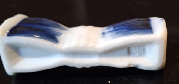 Nærbillede af en enkelt blå-hvid porcelænsholder med håndmalede blå striber og en hvid underside med et 'WHO'-stempel.