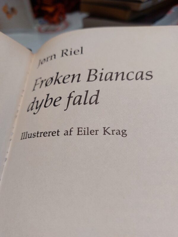 Nærbillede af bogryggen på 'Frøken Biancas dybe fald' af Jørn Riel, med grønt og beige design og gulddetaljer.