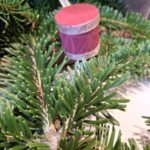 Et lille, håndlavet juletrommeophæng med et mønster af blå blomster og et matchende blåt satinbånd. Ophængt i juletræets grangrene.