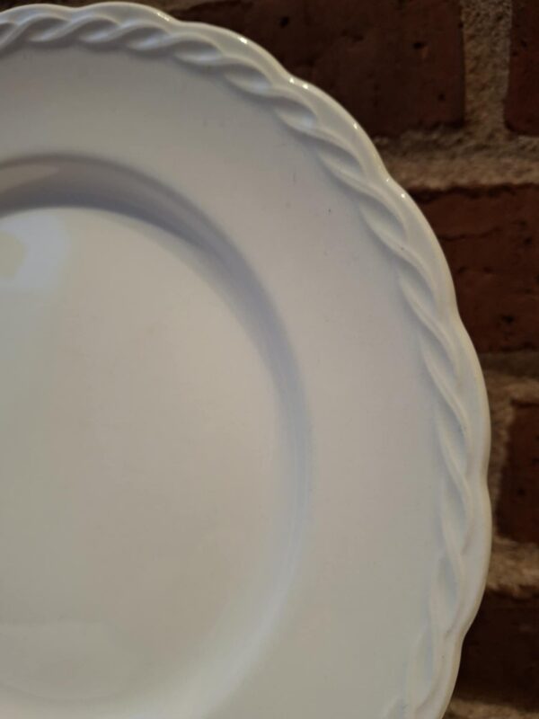Nærbillede af kanten på en hvid Hanley Ware 'Satin White' flad tallerken, der fremhæver den flettede reliefdetalje.