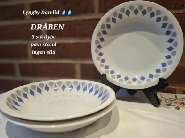 Tre dybe, hvide Lyngby Danild 'Dråben' tallerkener med blåt og gråt dråbemønster. To er stablet, en står oprejst.