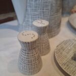 Nærbillede af to Rosenthal salt- og peberbøsser i hvid porcelæn med gråt grafisk mønster og små huller i toppen.