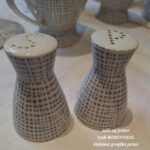 Et komplet Rosenthal stel i hvid porcelæn med et gråt grafisk mønster, inklusive kaffekande, sukkerskål, kopper, tallerkener, salt-og pebersæt og underkopper.