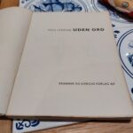 Nærbillede af forsiden på 'UDEN ORD' af Poul Strøyer, der fremhæver den ikoniske tegning og gule taleboble.