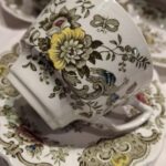 En elegant hvid Ridgway 'Windsor' kaffekop med et detaljeret blomster- og fuglemønster, der tydeligt viser krakeleringer og patina.