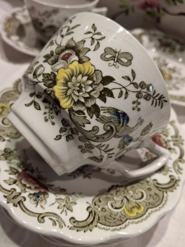 En elegant hvid Ridgway 'Windsor' kaffekop med et detaljeret blomster- og fuglemønster, der tydeligt viser krakeleringer og patina.