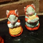 Nærbillede af to musselmalede keramikmusefigurer. Den ene mus bærer rød hue, den anden holder en kurv.