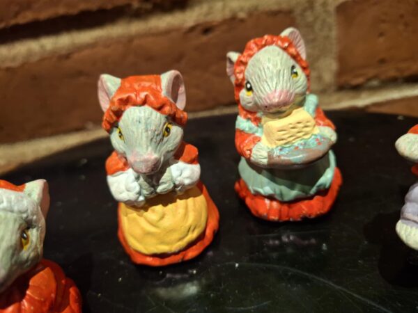 Nærbillede af to musselmalede keramikmusefigurer. Den ene mus bærer rød hue, den anden holder en kurv.