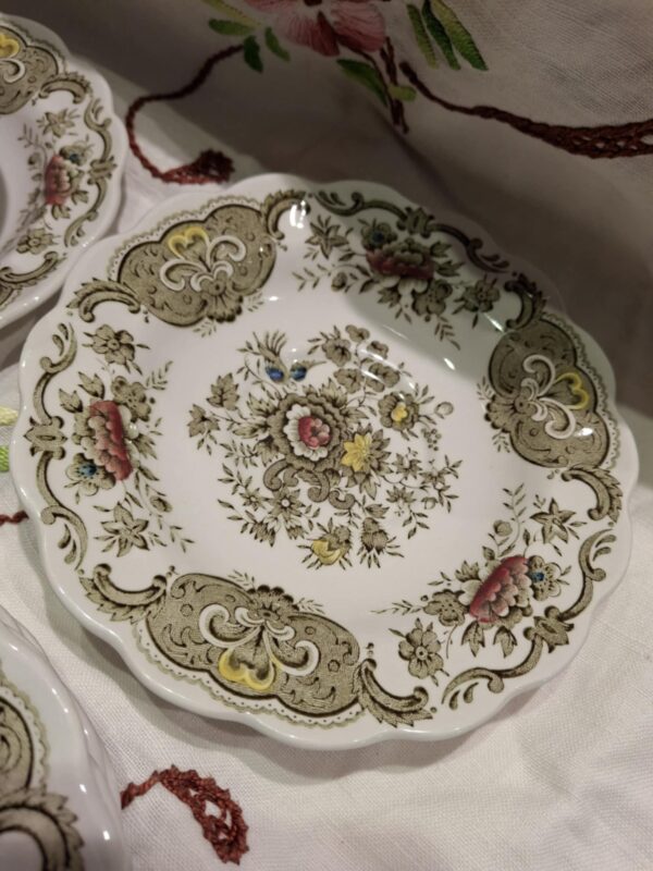 En Ridgway 'Windsor' underkop eller sidetallerken i hvid porcelæn med grønne og brune blomstermotiver og en bølget kant.