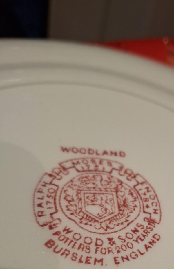 Nærbillede af bagsiden af en Woodland tallerken fra Wood & Sons med rødt stempel, der indikerer 'WOODLAND' og producentinformation.