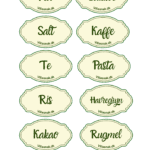 Nærbillede af 10 ovale, cremefarvede køkkenklistermærker med grøn kant til krukker, med teksten 'Mel', 'Sukker', 'Salt', 'Kaffe', 'Te', 'Pasta', 'Ris', 'Havregryn', 'Kakao' og 'Rugmel' på dansk.