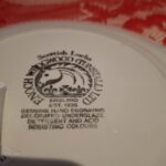 Bagsiden af den blå-hvide tallerken med tekst 'Scottish Lochs' og 'ENOCH WEDGWOOD (TUNSTALL) LTD', præget med ’England EST. 1835’.