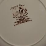 Bagsiden af en hvid 'Quiet Day' tallerken i fajance, der viser producentens stempel 'W.H. Grindley & Co Staffordshire England'.