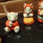 Nærbillede af to musselmalede keramikmusefigurer. Den ene mus bærer rød frakke og den anden sover i en gul kop.
