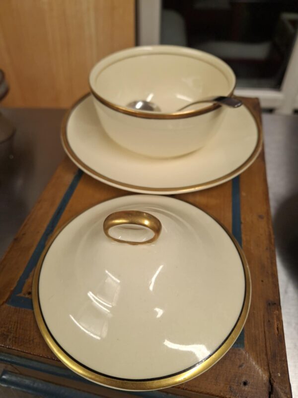 Komplet sart creme marmeladekrukkesæt fra Victorian Johnson Bros. bestående af krukke, låg med guldkant og en underskål, pyntet med guldkant og mørkeblå detaljer. En lille ske er også synlig.