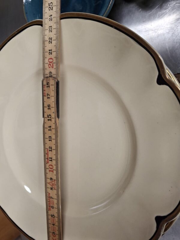En enkelt Johnson Bros. middagstallerken i cremefarvet porcelæn med guldkant og et målebånd, der viser en diameter på ca. 21 cm. Guldkanten viser let patina.