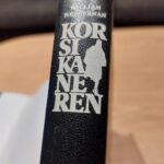Sort bogryg med cremefarvet tekst og silhuet