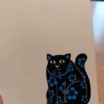 Illustration af sort kat med blå blomster
