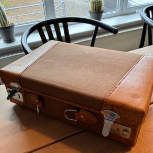 Vintage brun kuffert med læderdetaljer på bord