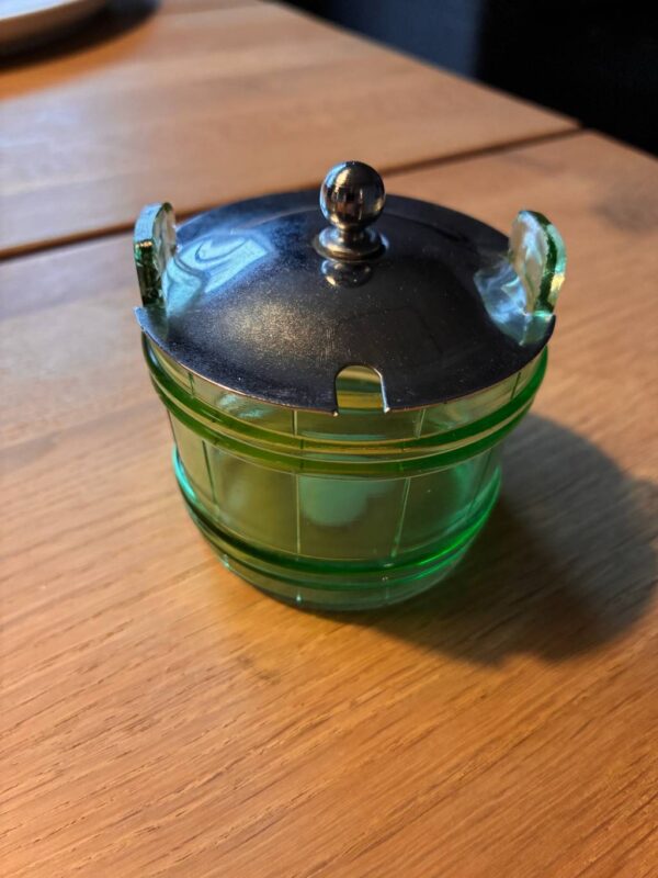 Grøn glasbeholder med sølvlåg på træbord