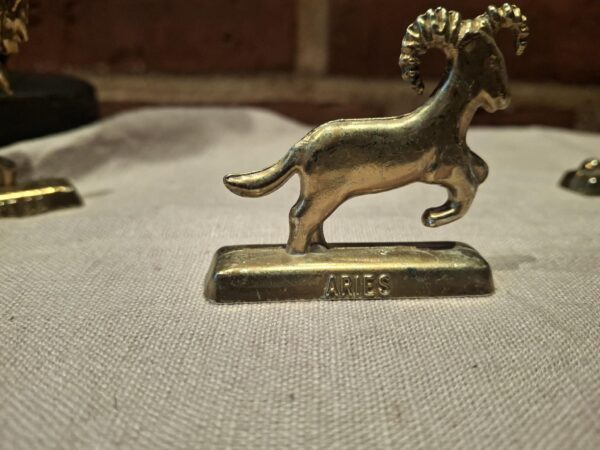 Messingfigur af vædder på beige klæde