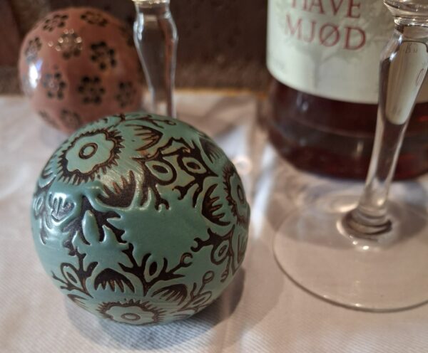 Blågrøn kugle og glas på bord med mønster