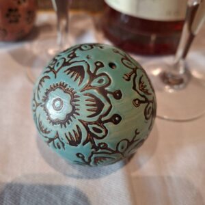 Dekorativ kugle med blågrøn og brun håndmaling på bord