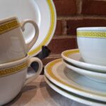 Kopper og tallerkener med gul bort på B&G kaffestel