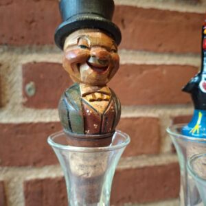 Smilende herrefigur med høj hat på træskænkeprop