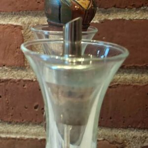 Skænketud med glasbeholder og trædetaljer foran murstensvæg