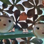 To glitrende kugler med ansigter foran metalbaggrund