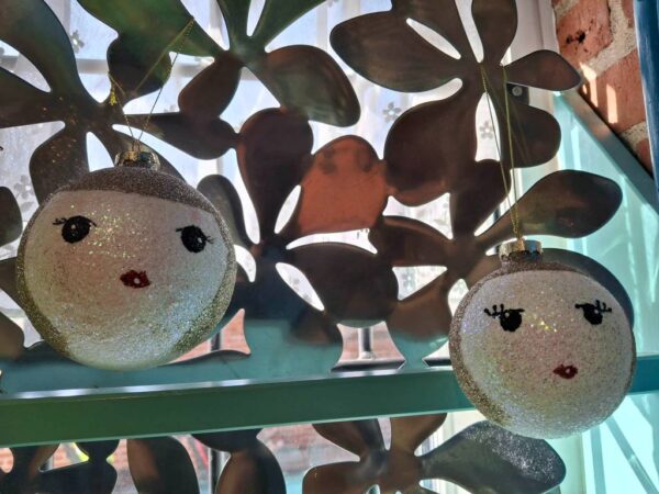 To glitrende kugler med ansigter foran metalbaggrund