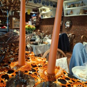 Orange stearinlys i metalstager på hæklet dug