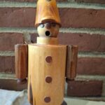 Træfigur af soldat i retro stil set forfra mod murstensvæg