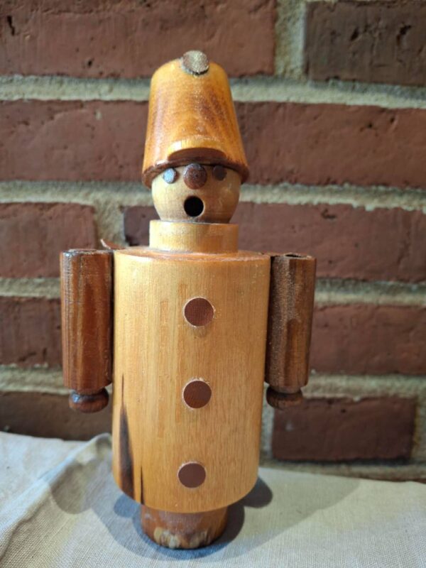 Træfigur af soldat i retro stil set forfra mod murstensvæg