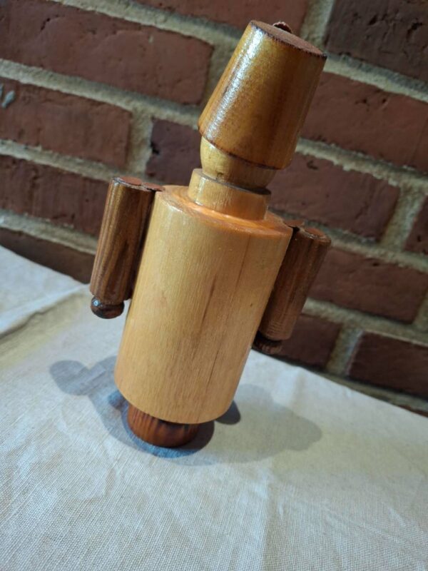 Træfigur af soldat i retro stil set fra siden mod murstensvæg