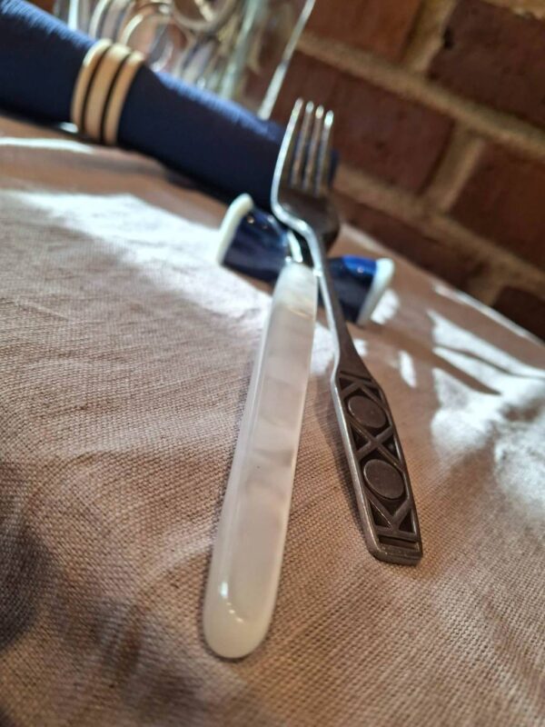 Kniv med hvid perlemorsskaft og metallisk dekoration