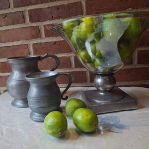 Sæt med 2 tin kander i rustik stil på hvid dug med limefrugter og glasbowle