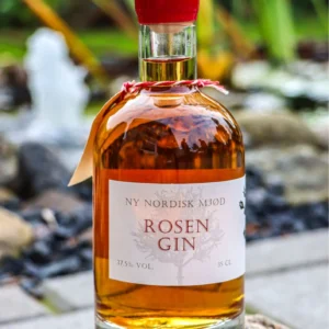 En flaske 'NY NORDISK MJØD ROSEN GIN' på 35 cl med ravfarvet væske og rød forsegling, placeret udendørs på en sten.